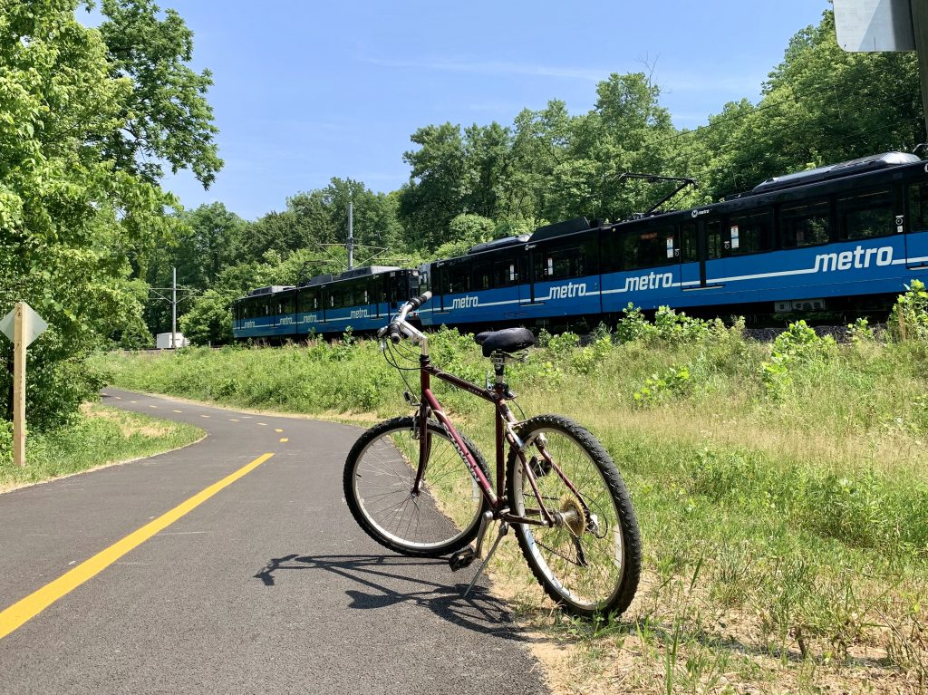 Bike on the new MetroBikeLink Trail expansion, with a MetroLink train passing by in the background