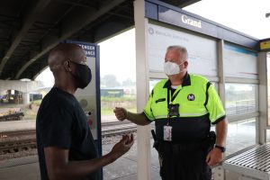 Security personnel talking to a passenger on a MetroLink platform. 