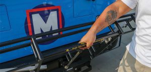 Bring your bike on MetroBus step 1: Man squeezing the center handle to pull the bike rack down.