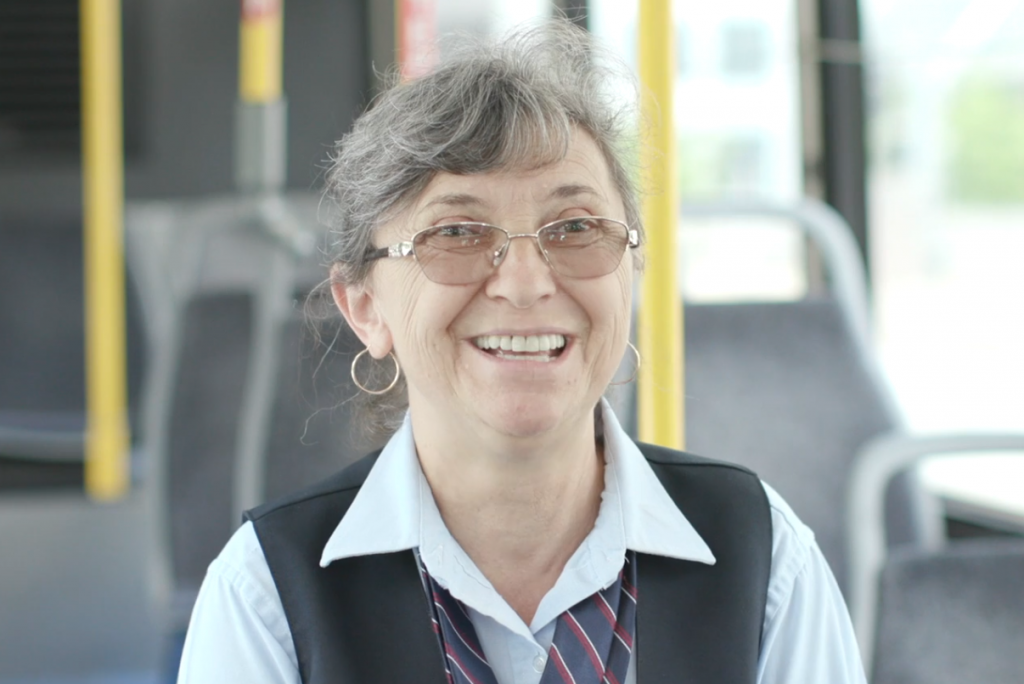 Photo of MetroBus Operator Violeta sitting on a bus and smiling at the camera