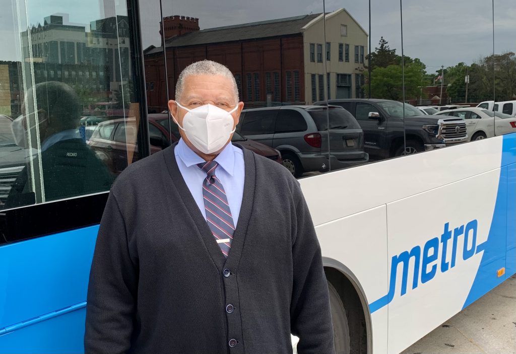 Image of MetroBus Operator Orvin standing in front of a bus and wearing a mask