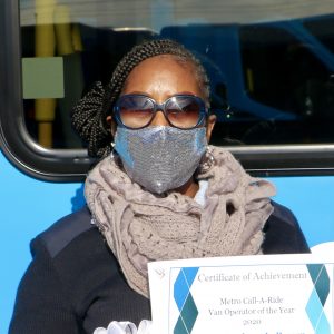 Metro Call-A-Ride 2020 Operator of the Year Barbara, smiling at the camera and holding her certificate of achievement