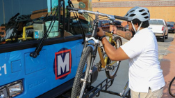 Man lifting up a bike to place the tires into the bike rack slots.