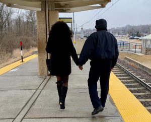 Passenger Profile: Lawanda and Jose walking away from the camera on the Fairview Heights MetroLink platform, holding hands