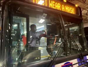 Employee cleaning the interior of a bus with new disinfecting technology. The photo was taken from the outside of the bus, looking in. 