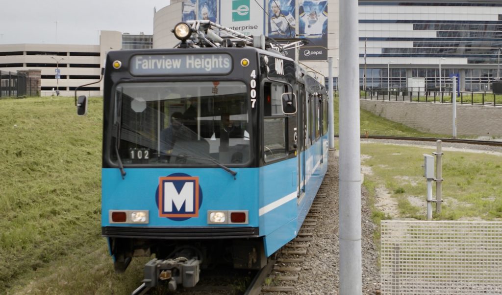 A MetroLink train pulls into the Civic Center MetroLink station. The Enterprise Center appears into the background.