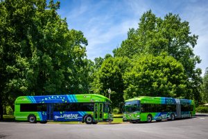 60-foot and 40-foot electric buses on the street with trees behind them