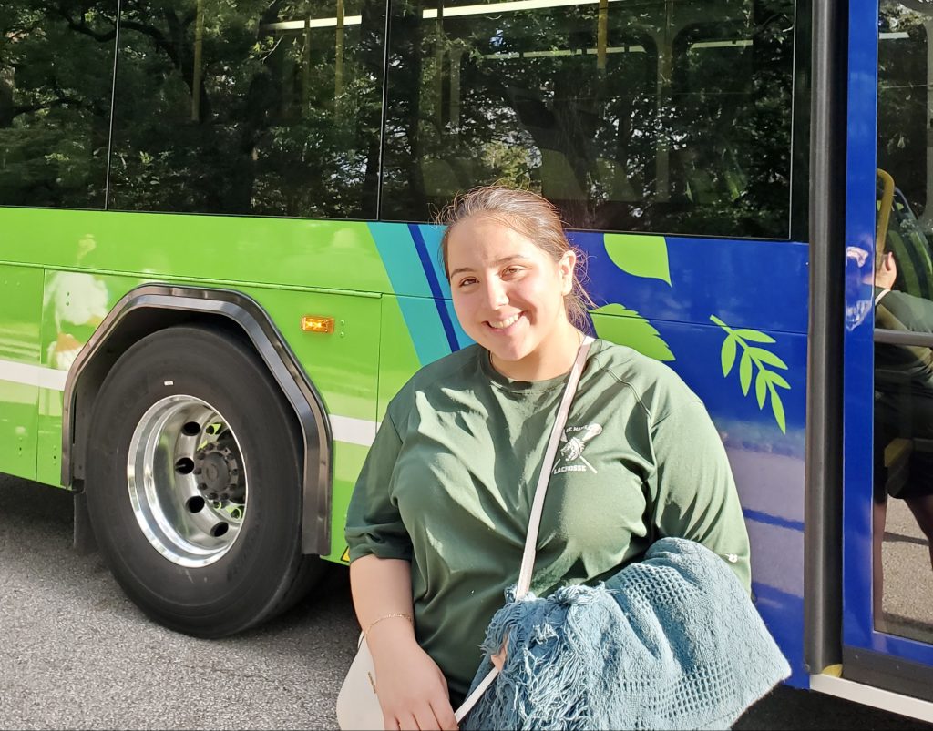 Passenger Asia standing in front of an electric bus