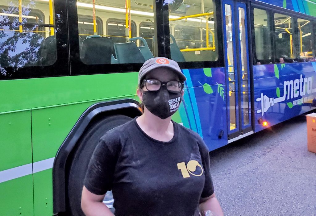 Image of passenger Kayle during the evening standing in front of our new battery electric bus