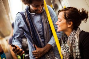 Man and woman staring at a mobile phone while on the train