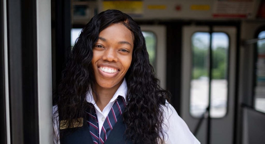 MetroLink Operator Shaftia standing on a train and smiling at the camera