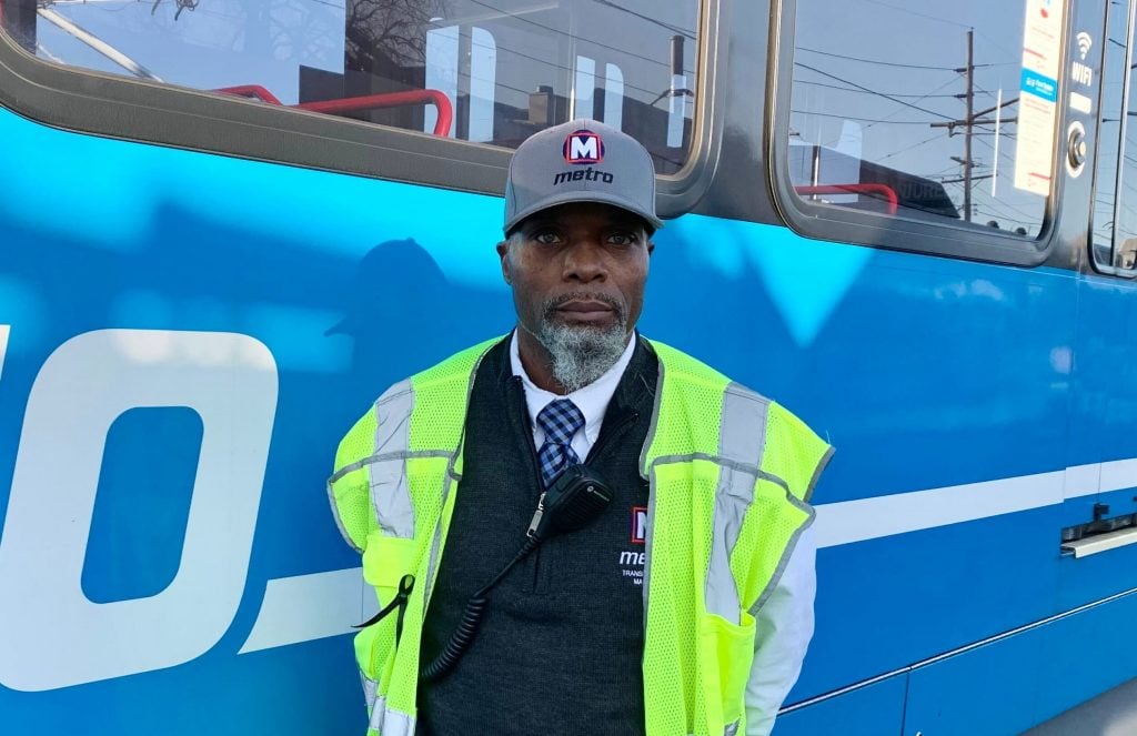 Team member Diondre standing in front of a MetroLink train at the yards