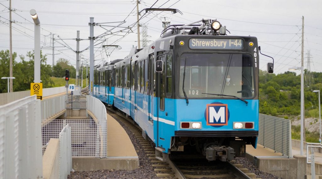 A blue, MetroLink light rail vehicle traveling on the tracks.