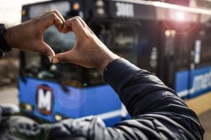 Man's hand making a heart in front of a MetroLink train