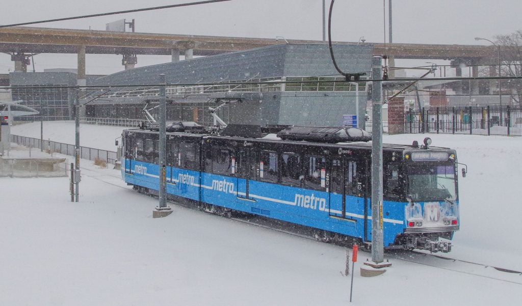 Single-car MetroLink train approaching Civic Center Transit Center during a winter snow storm