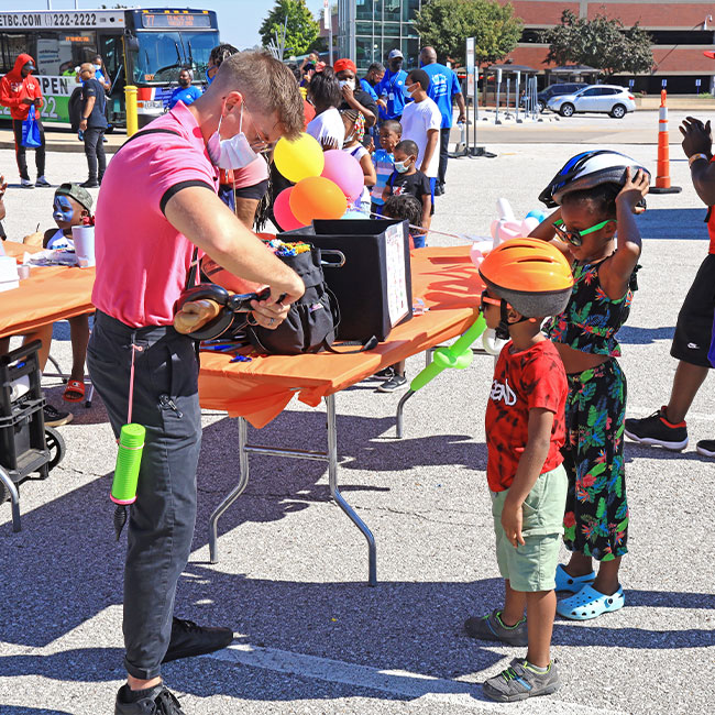 MetroFest team member making balloon animals for children.