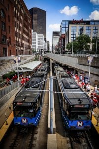 Photo from above the Stadium Station looking onto the tracks with two blue trains stopped, and Cardinals fans exiting the train