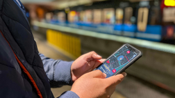 Passenger holding phone Transit app train in background