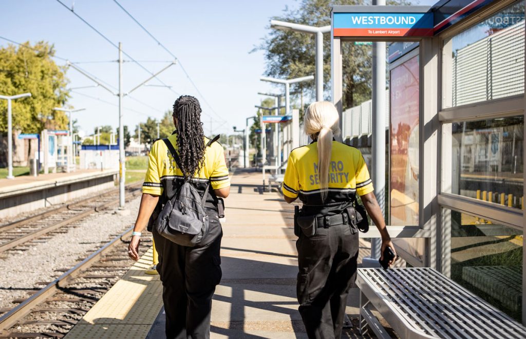 Photo of two security team members walking away from the camera on the platform at Delmar MetroLink Station