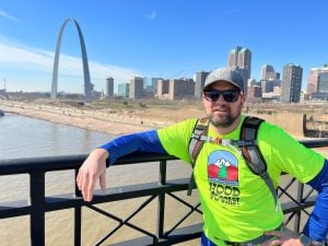 A runner poses with the St. Louis skyline behind him.