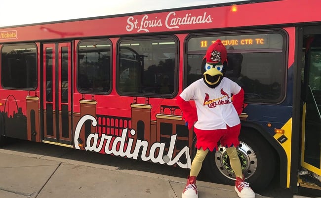 Photo of the Fredbird mascot outside of a Metro bus decorated with a St. Louis Cardinals theme