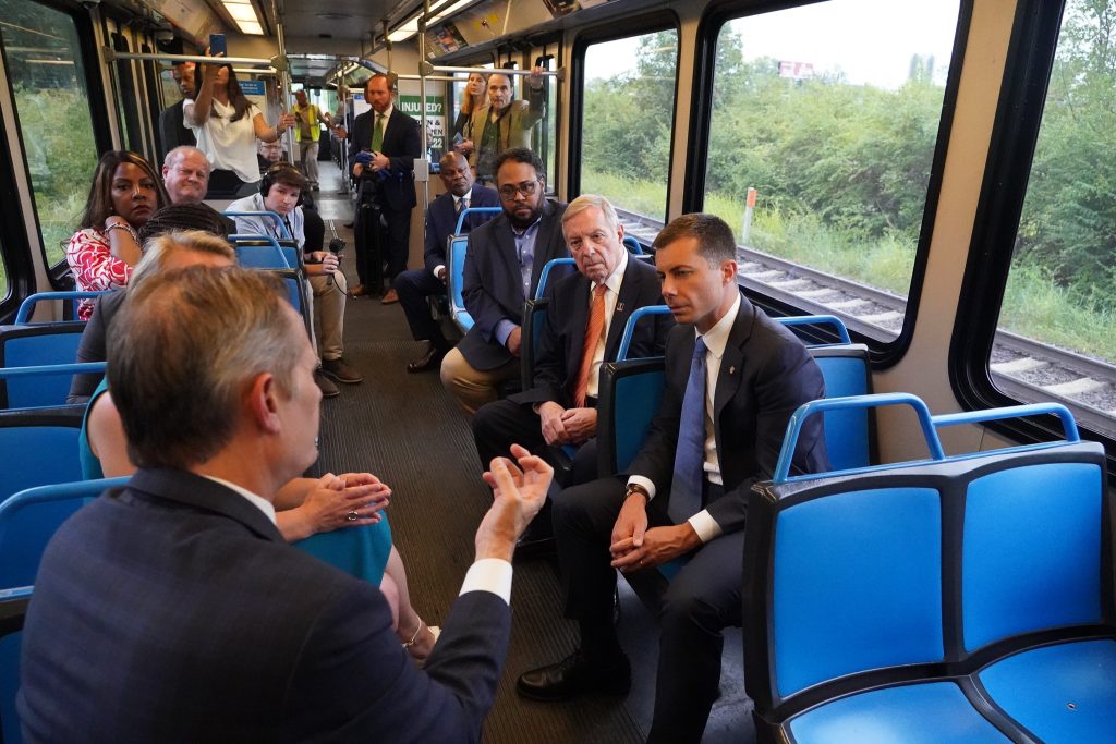 BSD President & CEO Taulby Roach talks to U.S. Secretary of Transportation Pete Buttigieg and others onboard a MetroLink train