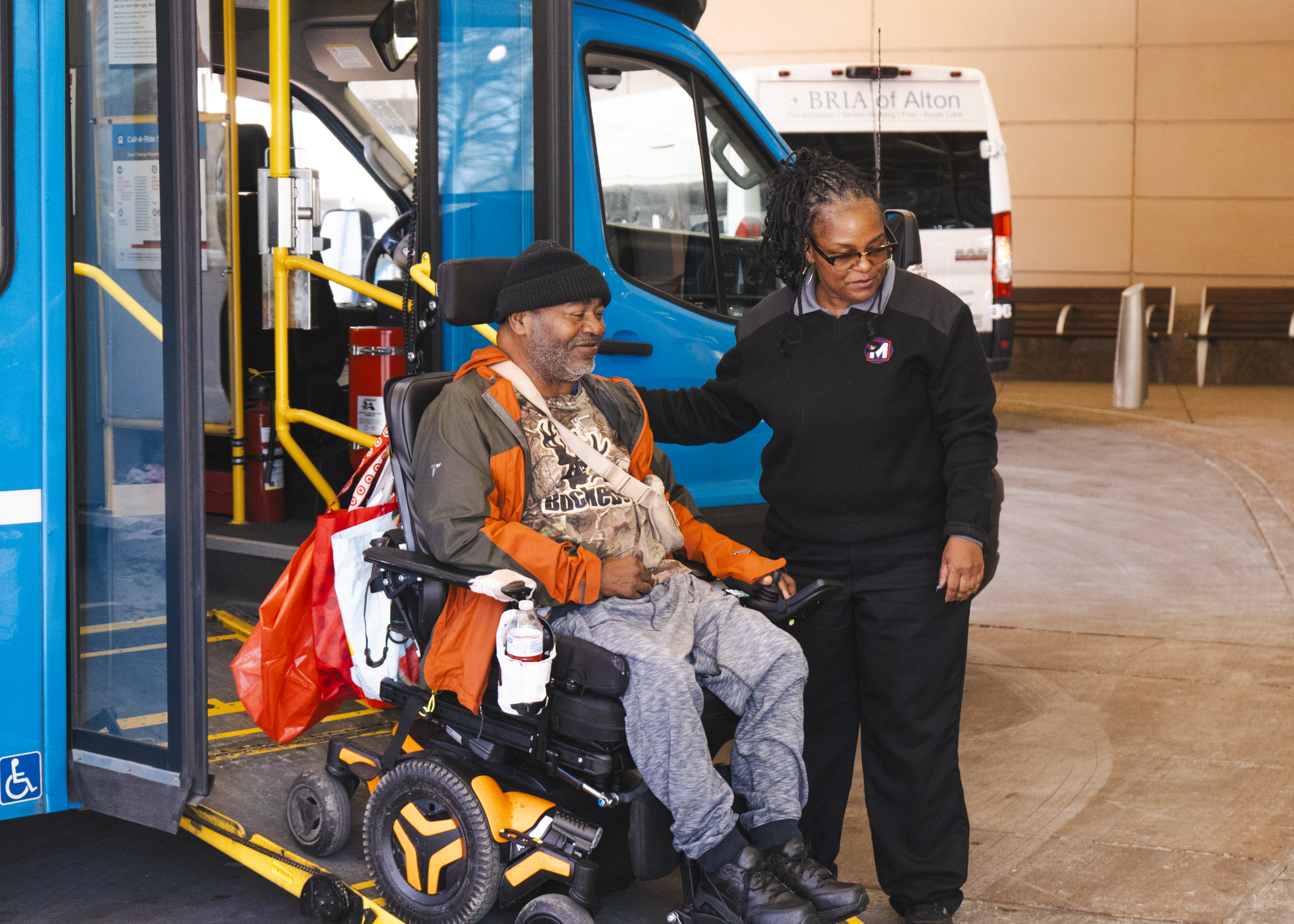 Call-A-Ride Operator assistance rider in a mobility device down a wheelchair lift ramp